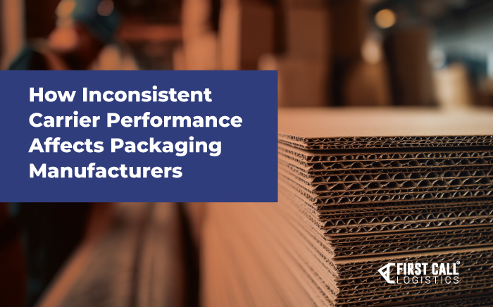 Close up of stacked corrugated cardboard sheets in a packaging facility with a worker in the background.